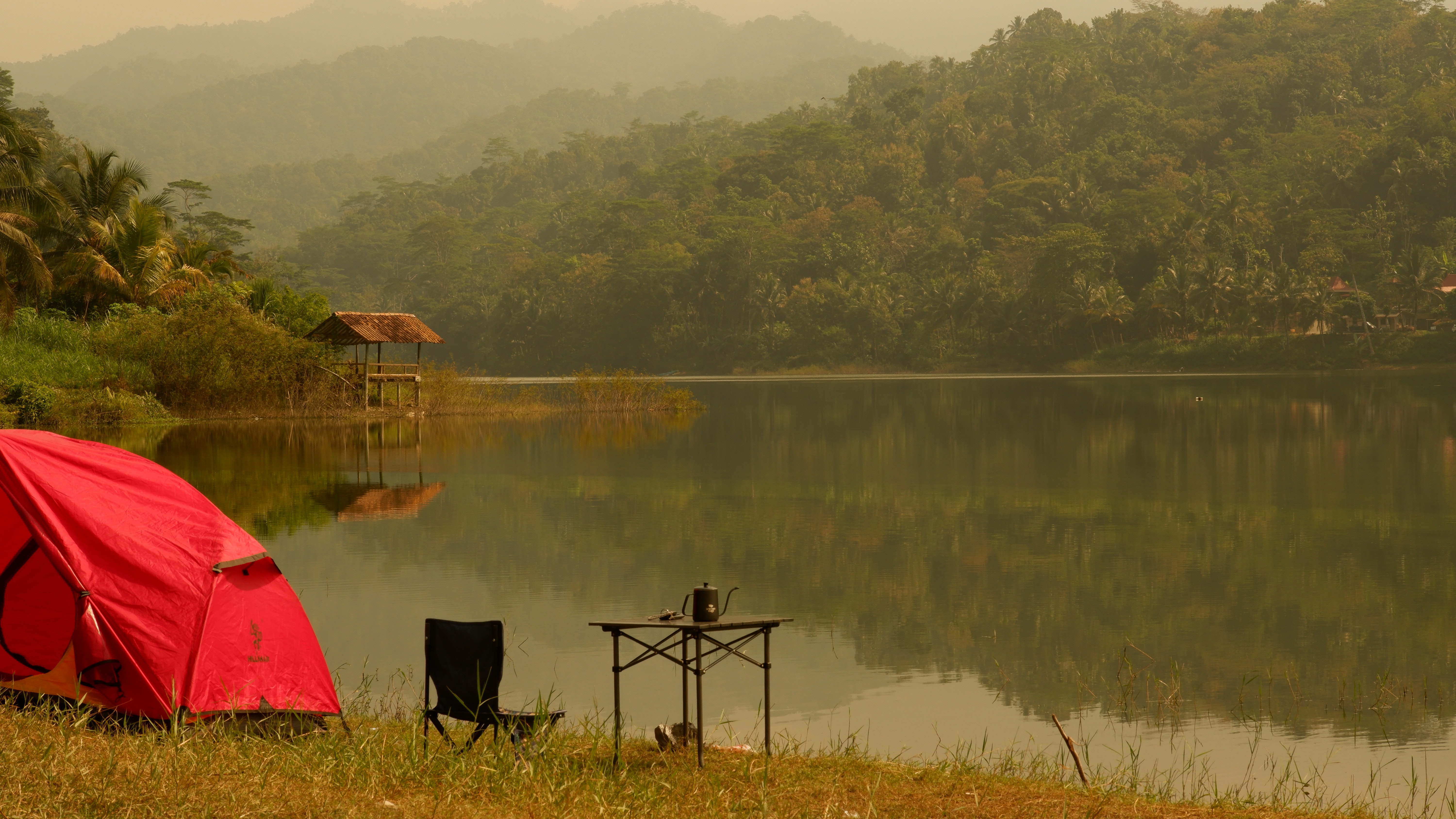 Camp chair and tent on river bank