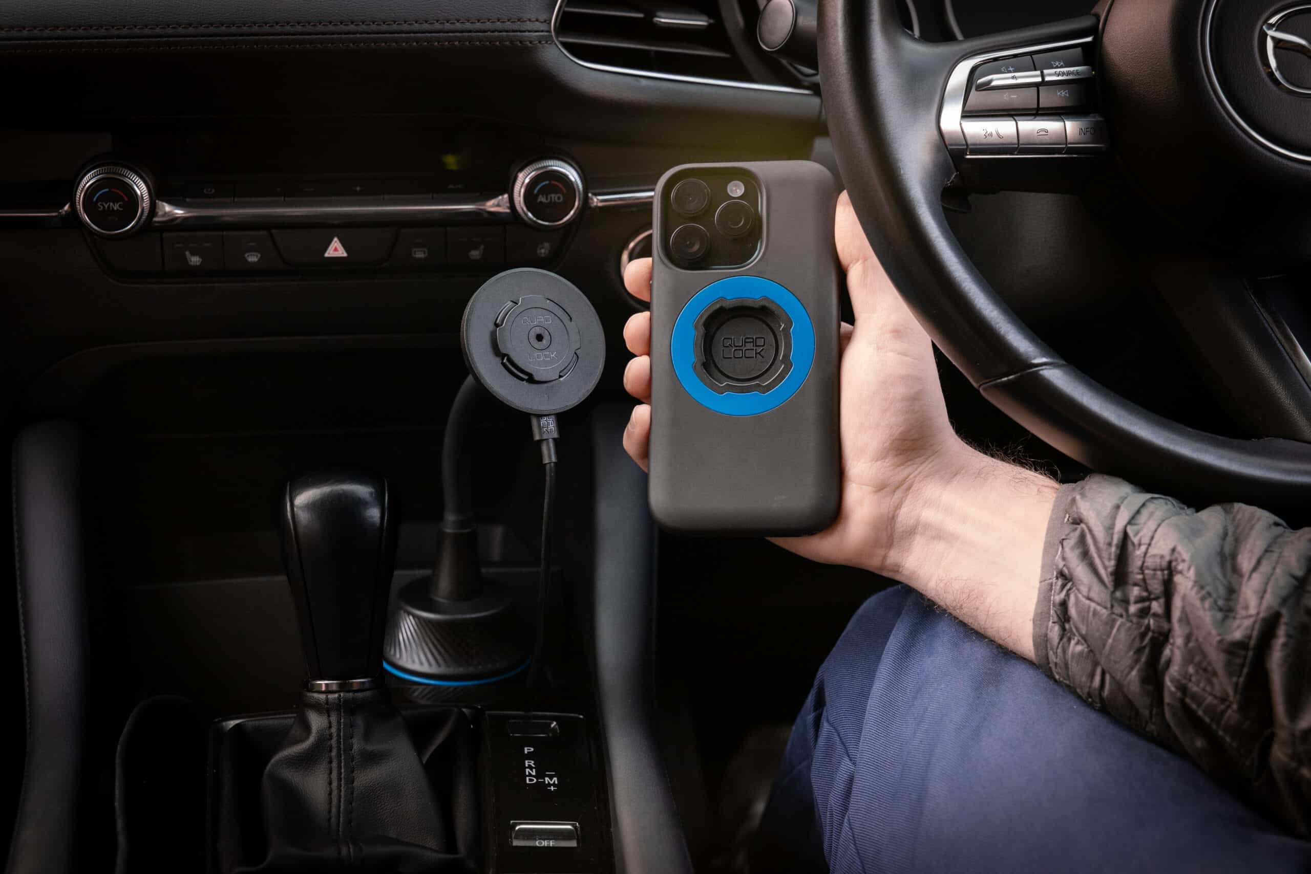 Quad Lock wireless charging cup holder mount installed in Mazda vehicle with smartphone charging