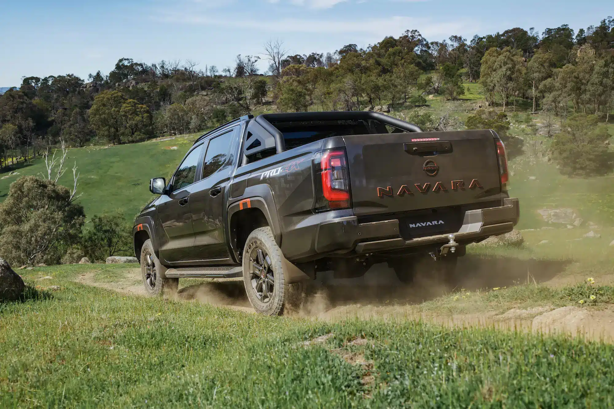 2026 Nissan Navara PRO-4X rear three-quarter view driving on dirt