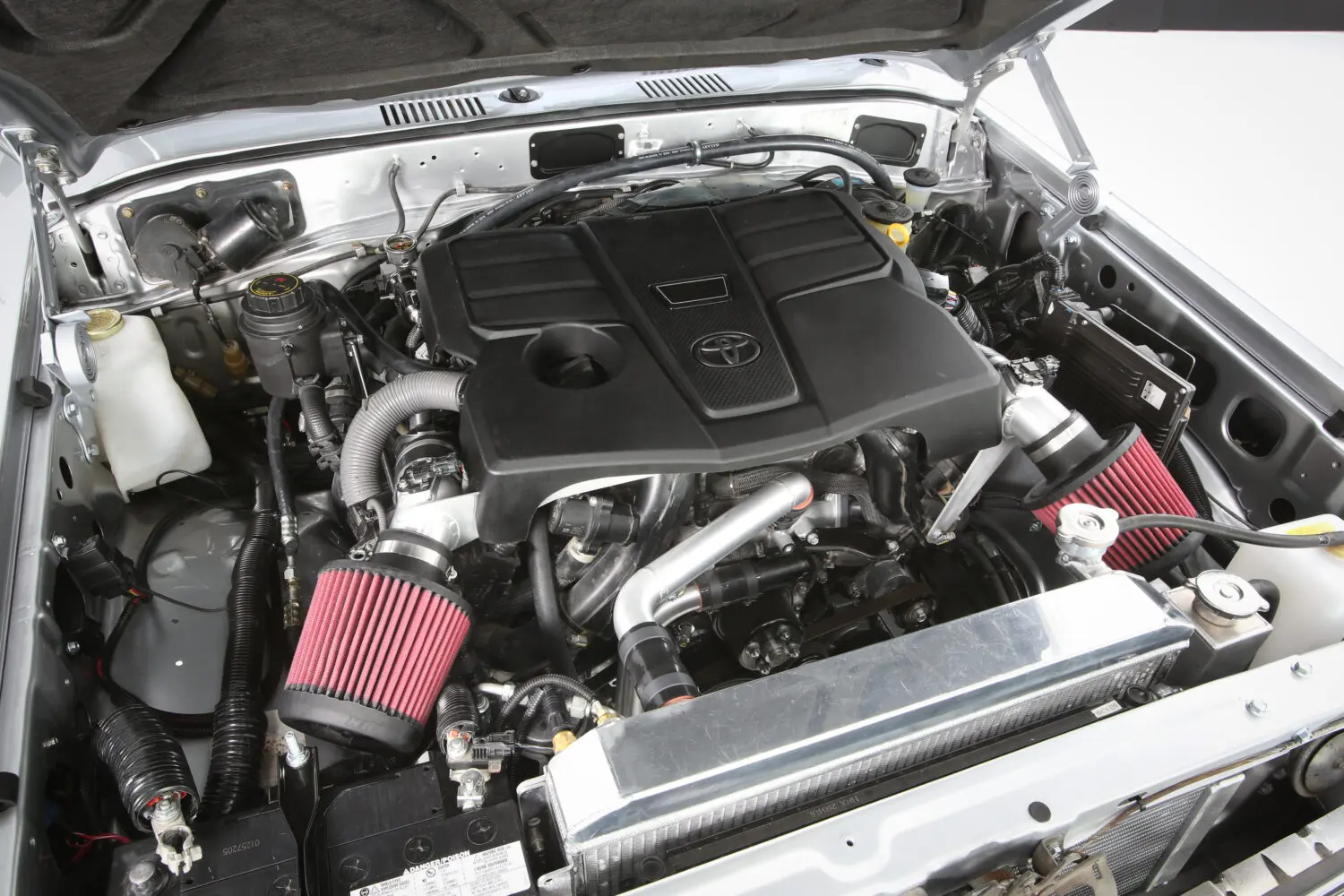 60 Series Land Cruiser engine bay showing twin-turbo V6 installation with custom adapter plates and motor mounts