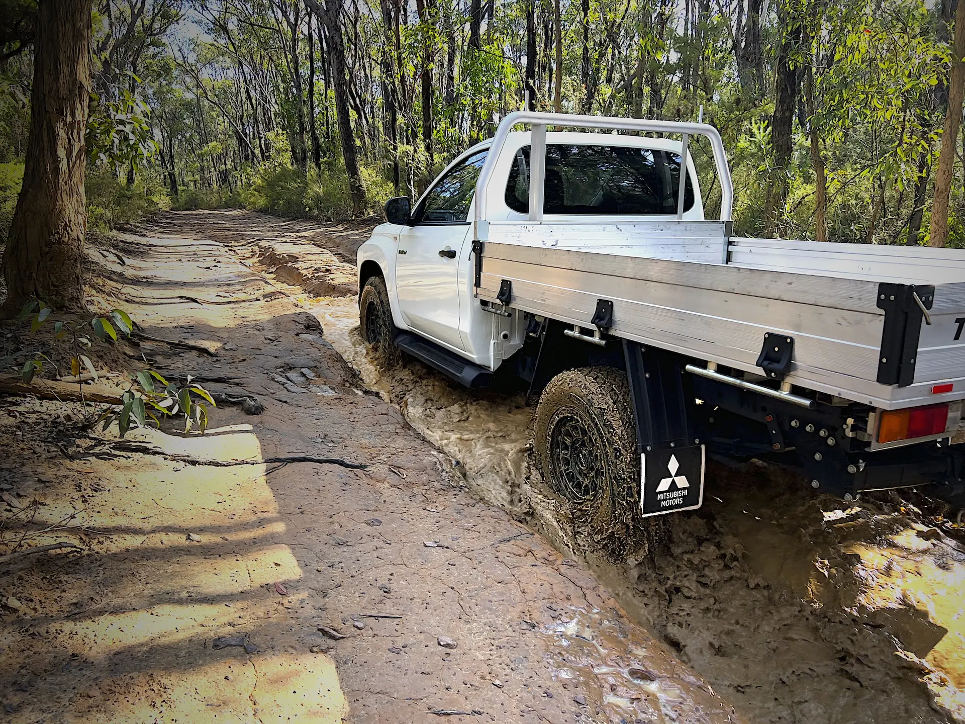Predator New Mutant XATs: White Triton driving through a muddy water crossing showing tyre self-cleaning